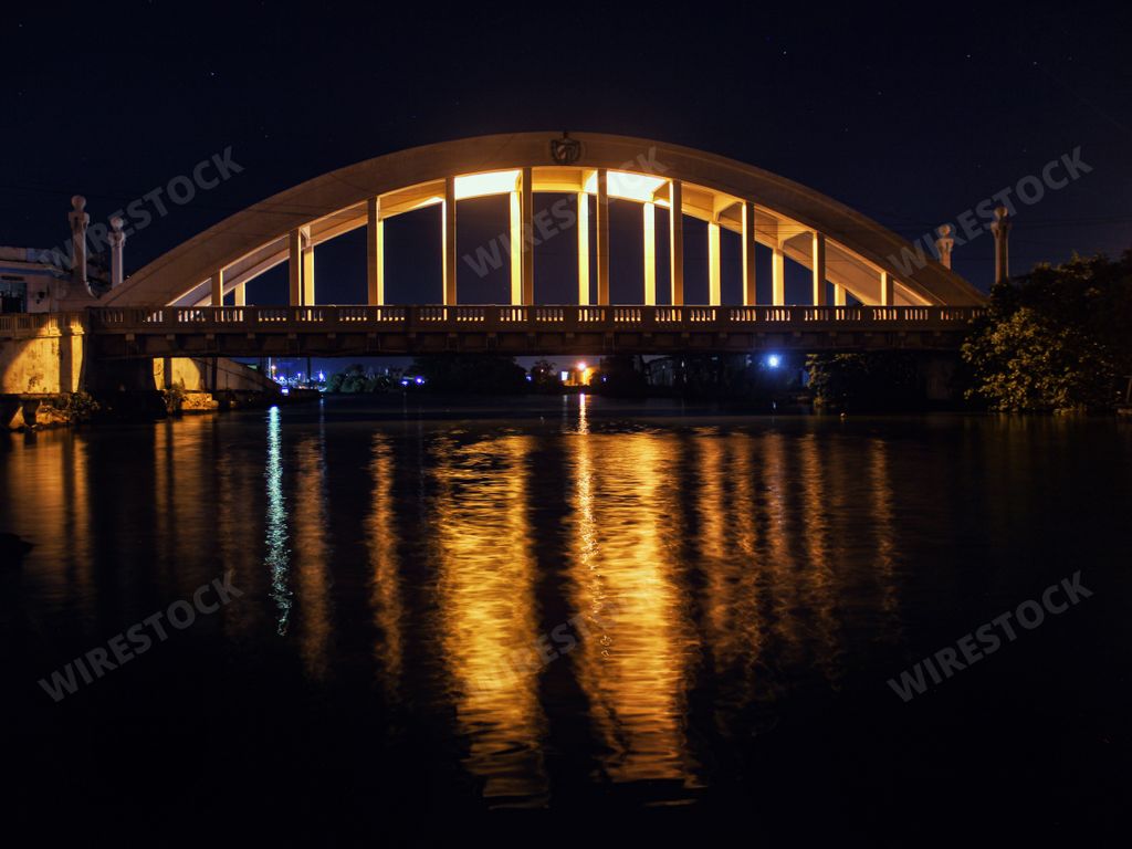 A beautiful shot of the San Luis Bridge at night with reflections of street lights in the river