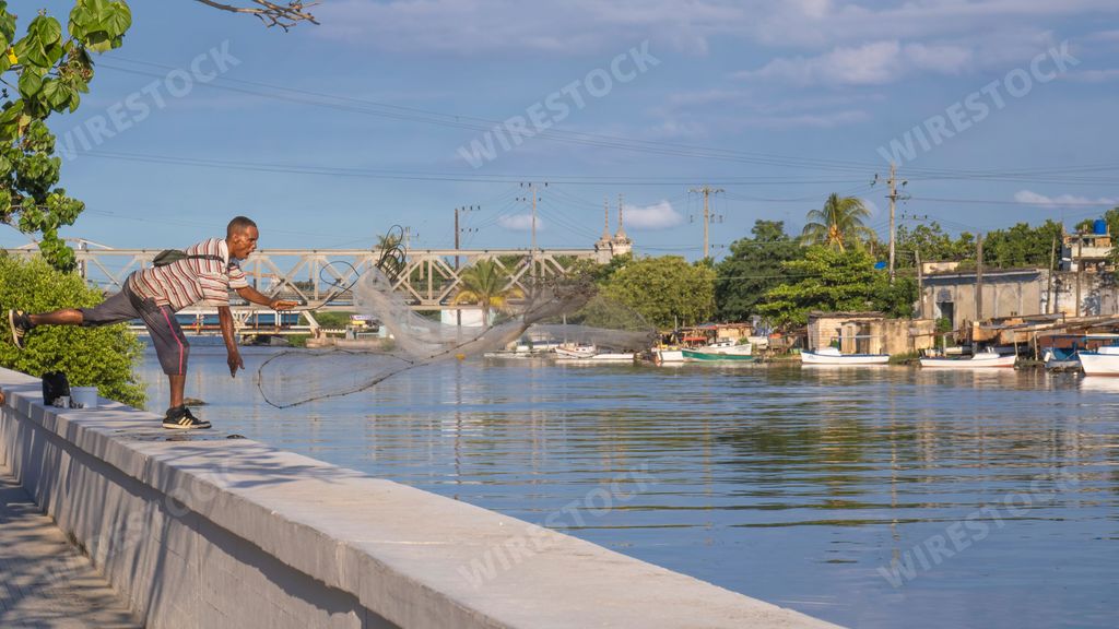 A Fisherman throwing fishing net during sunrise