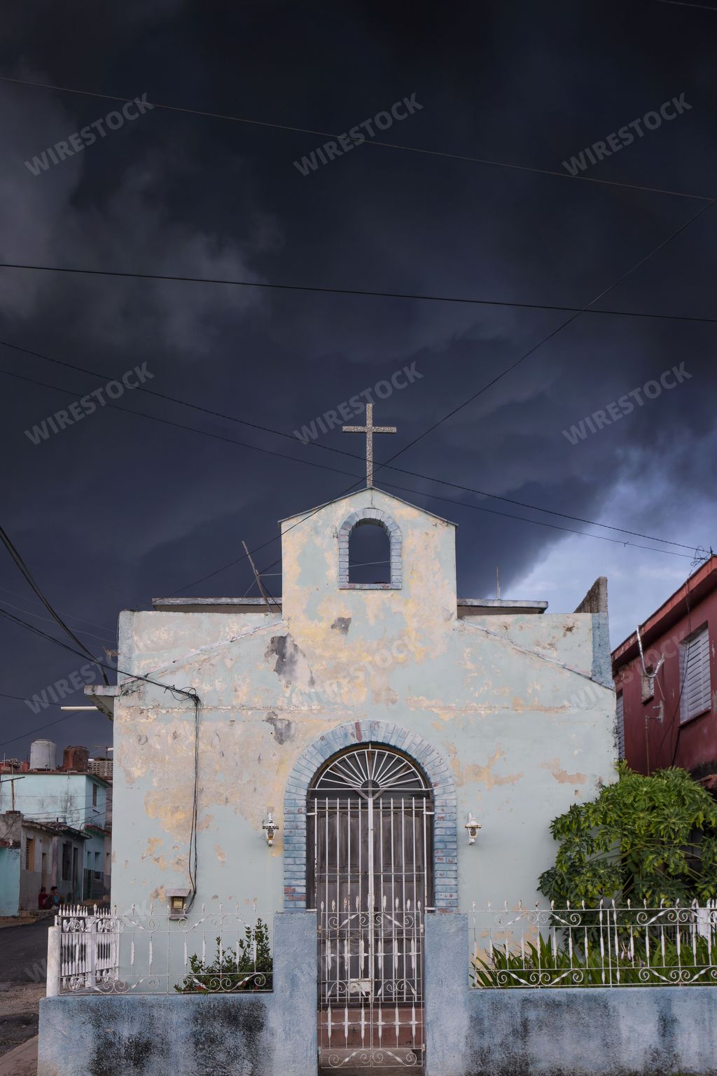 A vertical shot of a church with a huge cross and storm in the background
