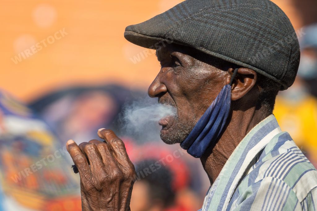 A selective focus shot of an old Cuban male smoking a tobacco