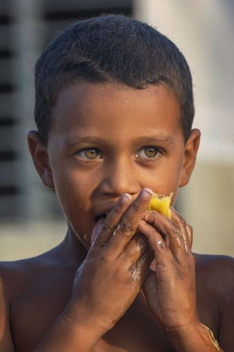 Poor Cuban girl eating mango Stock photo | Wirestock