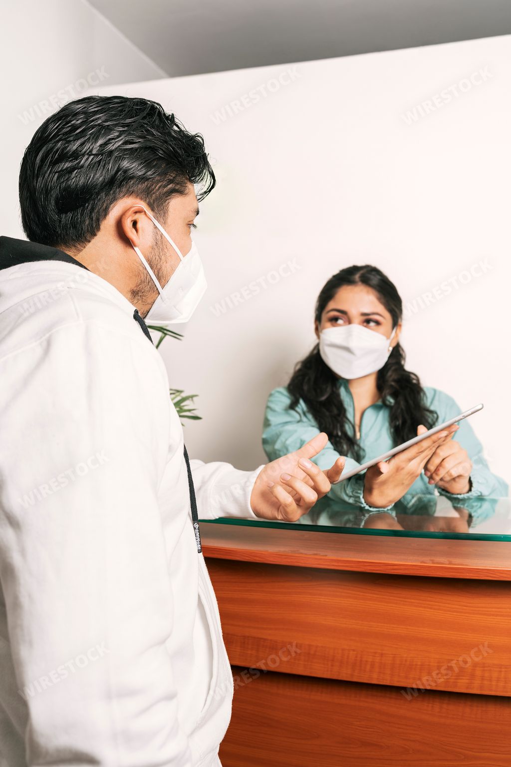 A young latina receptionist talking to a man in a dental clinic