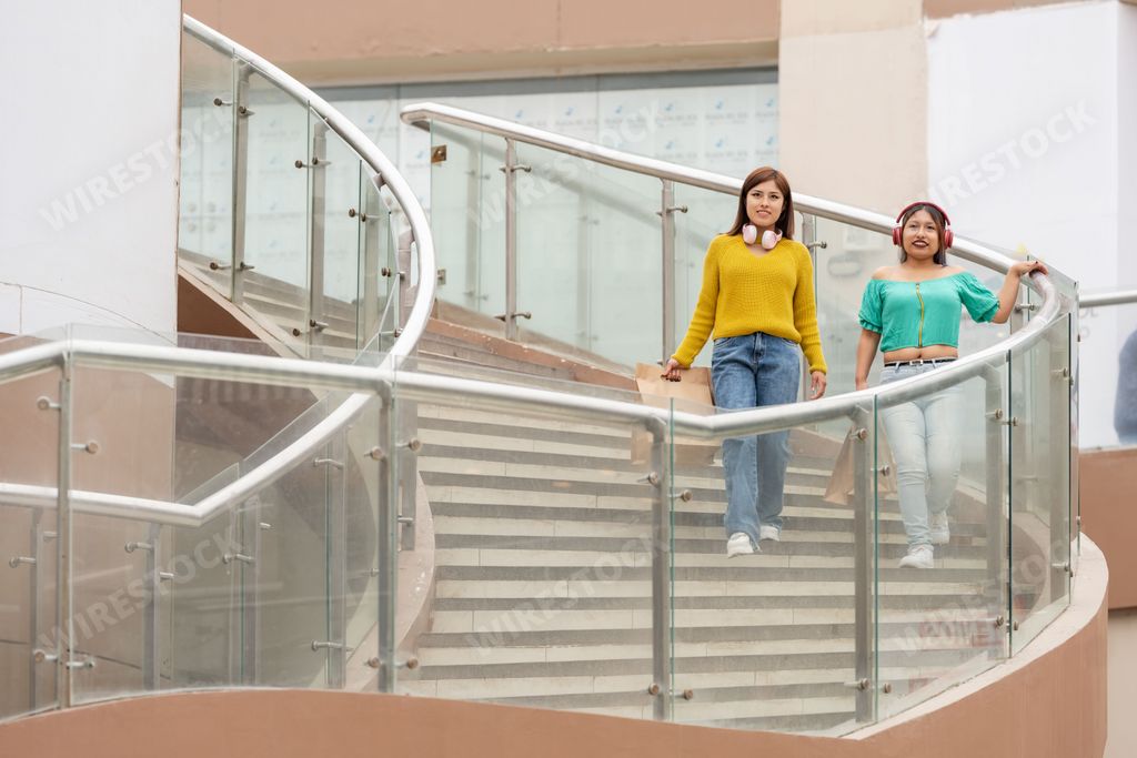 Two latina friends with headphones buying in a shopping center