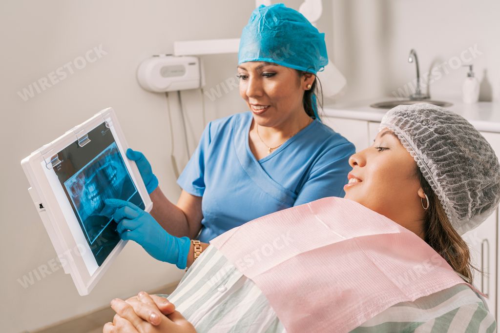 A female dentist showing her patient an x-ray of her mouth at a consultation