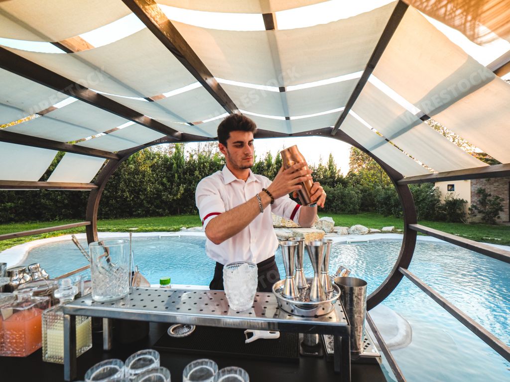 A young Caucasian barman making a refreshing cocktail outdoors at an event