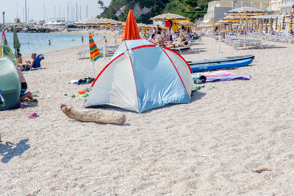 People , mostly italian local tourist, enjoys beach in summertime following distancing rules at the adriatic sea