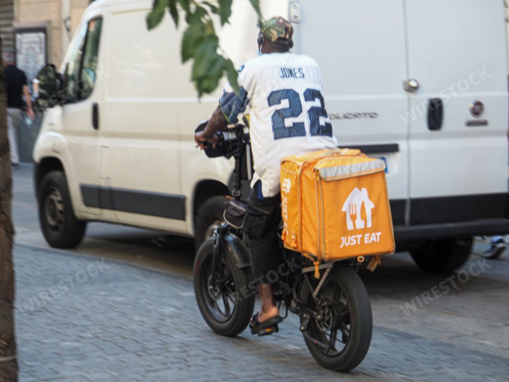 A food delivery rider on a bike at work in Milan city center