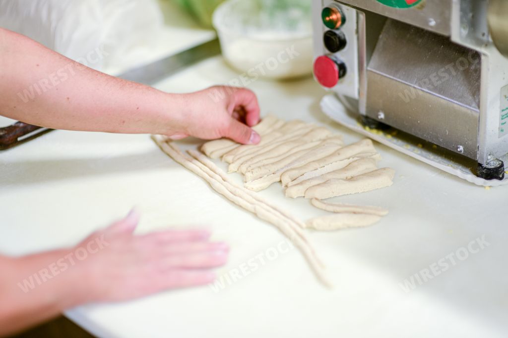 Adult caucasian woman preparing pisarei, italian extruded traditional pasta from Piacenza, Italy. Recipe includes bread cumbs, flour, water and salt.