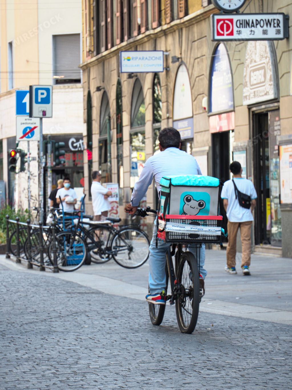 A rear view of a rider delivering food ordered using a delivery companies app in Milan, Italy