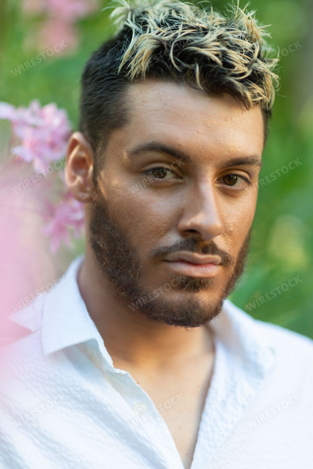 A vertical shot of a young attractive Caucasian guy with ombre hair from Italy in a garden