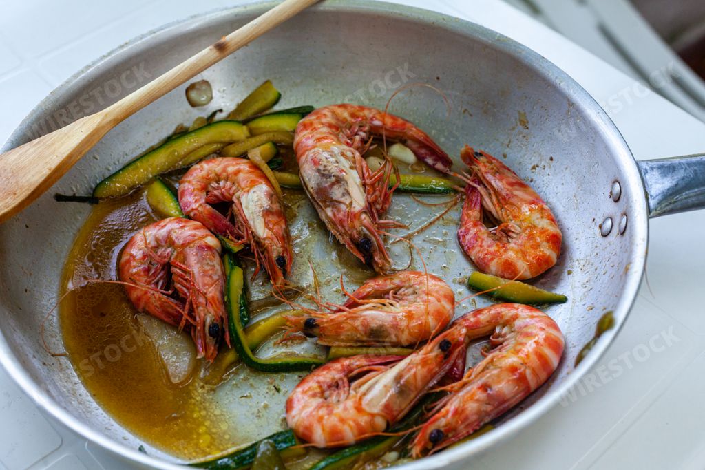 a closeup shot of wild Adriatic sea prawns in a silver pan with a wooden spoon