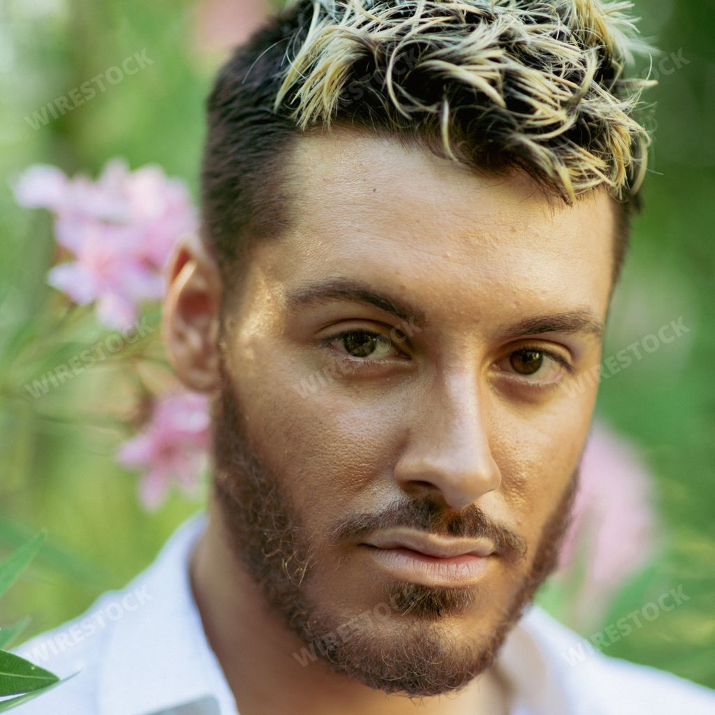 A vertical shot of a young attractive Caucasian guy with ombre hair from Italy in a garden