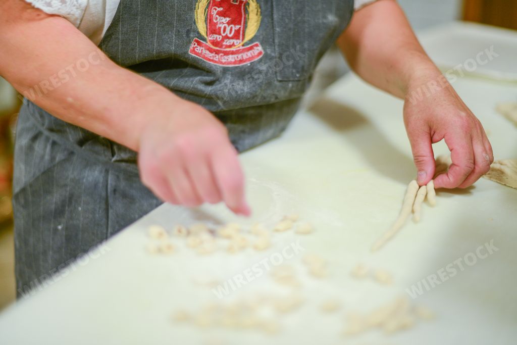 Woman making pisarei,  tradtional pasta , extruded fresh pasta, made of bread crumbs, water, soft wheat four type 00, salt.