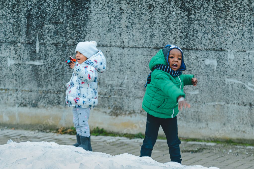 A scene of two African American kids playing with the snow outdoors