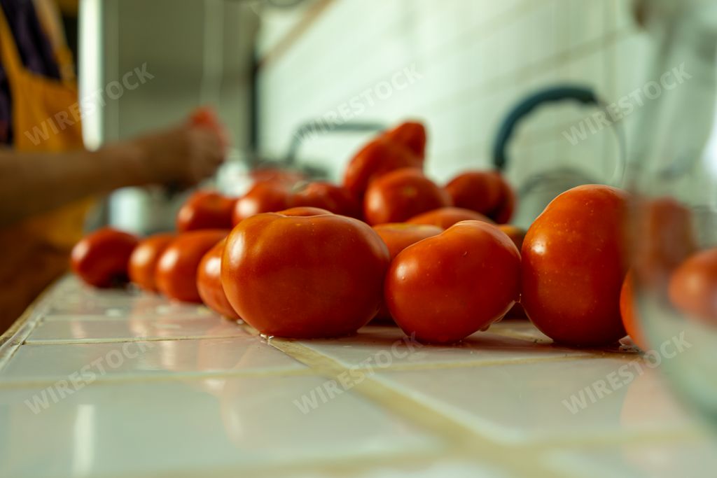 A woman washing tomatoes to prepare tomato sauce in the kitchen