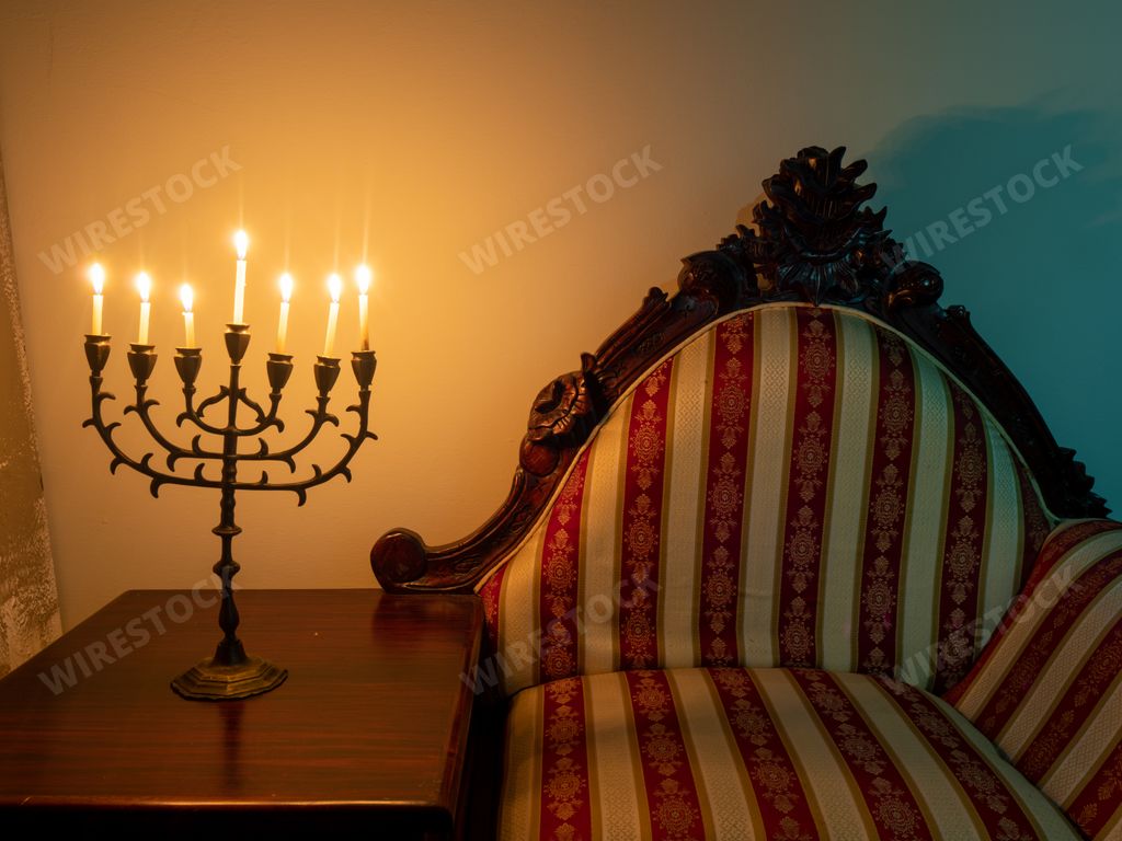 A closeup shot of a seven-branched candelabra with burning candles on the wooden table for Hanukkah