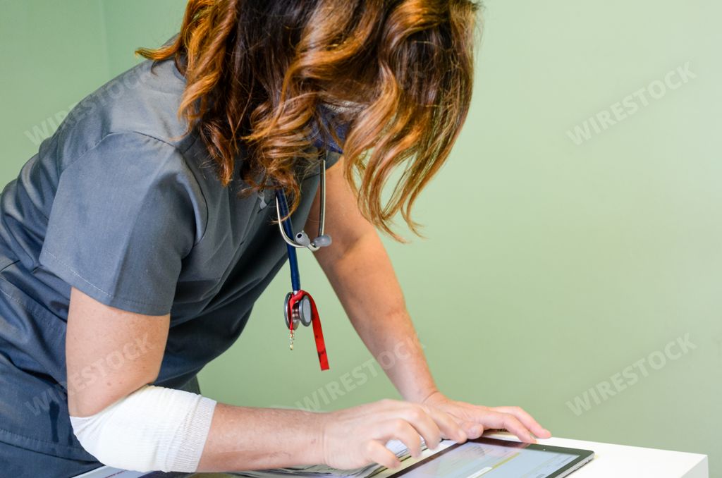 A Caucasian female doctor wearing a facemask on a gray background