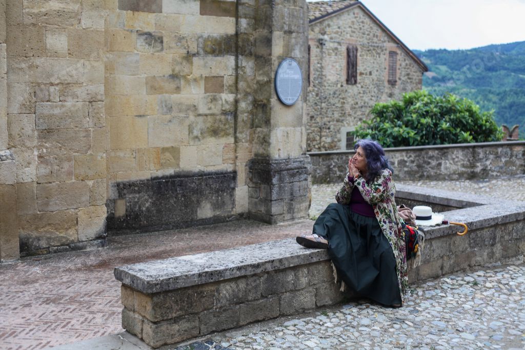 A senior woman touring in the medieval village of Vigoleno, Piacenza, Italy, during summer