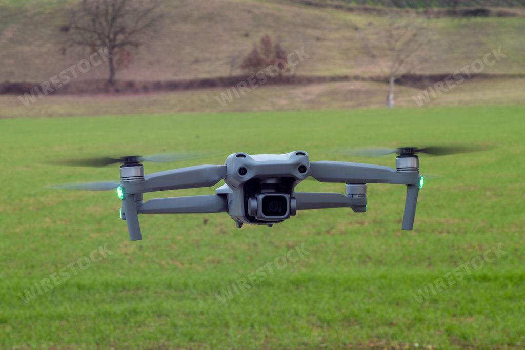 This stock photo features a small aerial device flying over a grass field