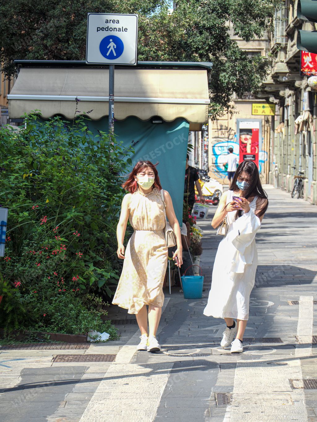 A vertical shot of two young Chinese girls on the street in Chinatown in Milan, Italy, summer 2021
