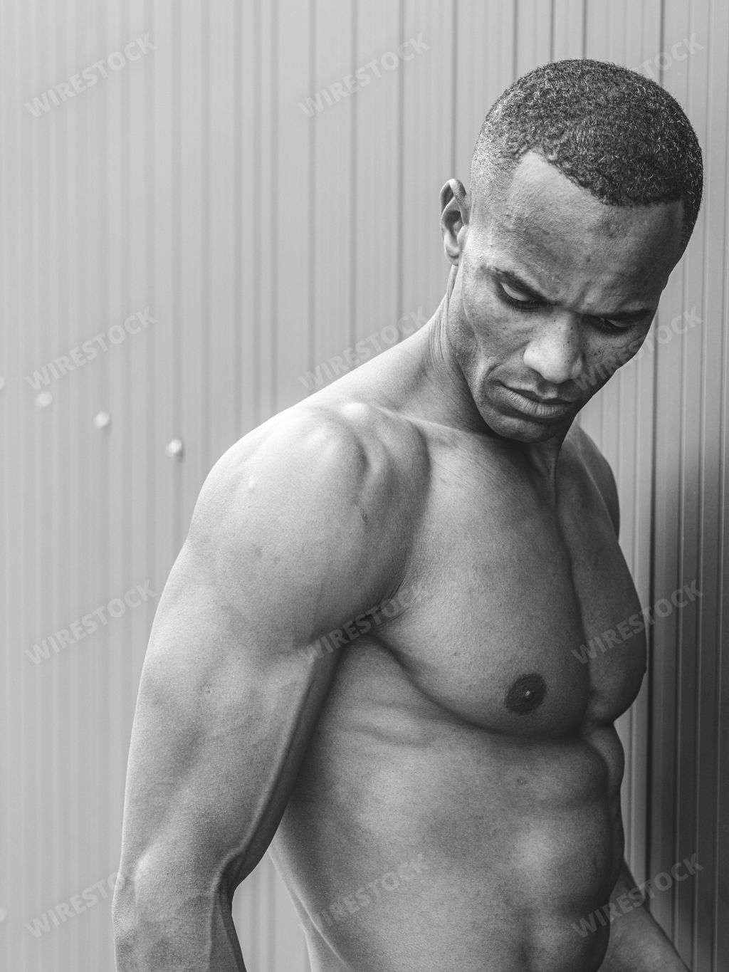 A grayscale shot of a muscular Italian man posing shirtless