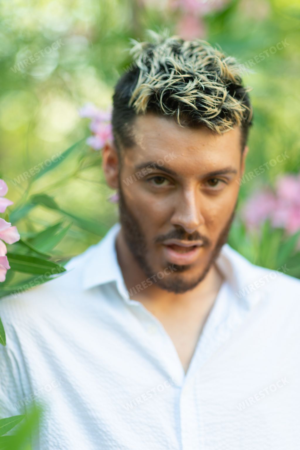 A vertical shot of a young attractive Caucasian guy from Italy in a garden