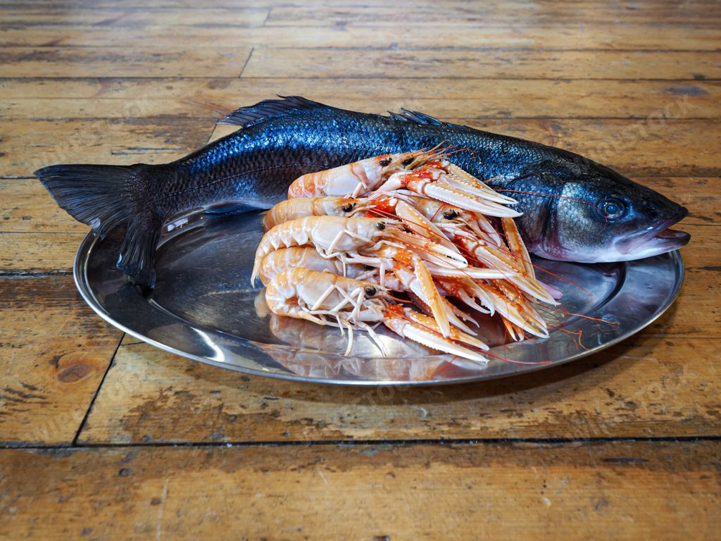 A closeup of fresh Atlantic prawns and a fish on a plate on a table