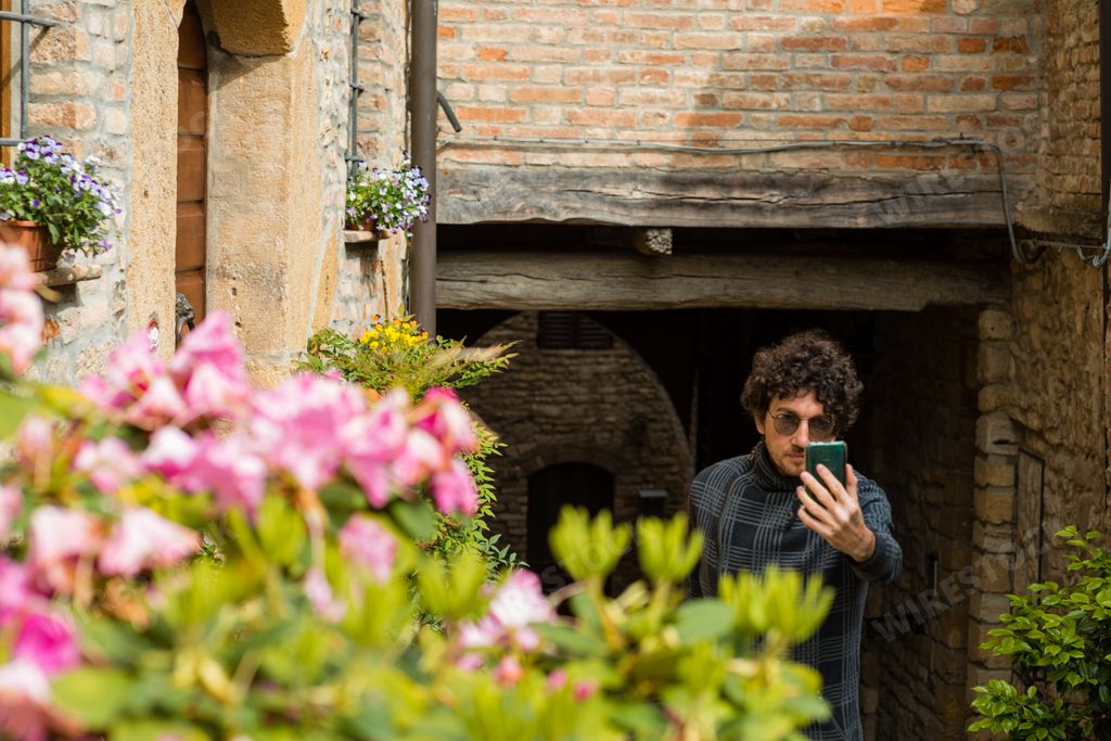 A young Italian man with curly hair and sunglasses taking a selfie