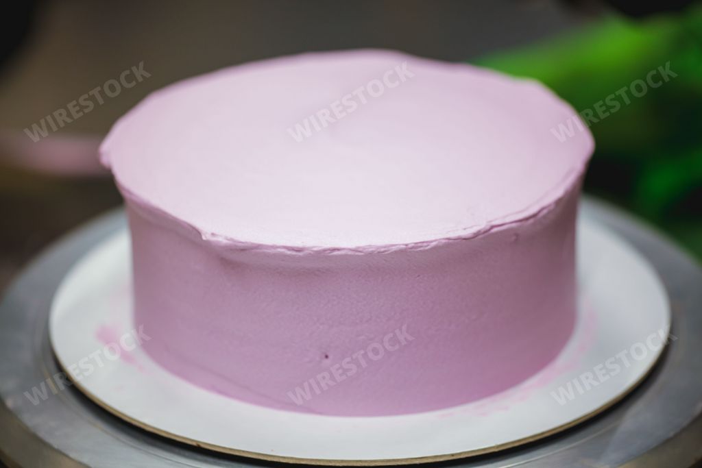 A closeup shot of a blank cake covered in baby pink frosting