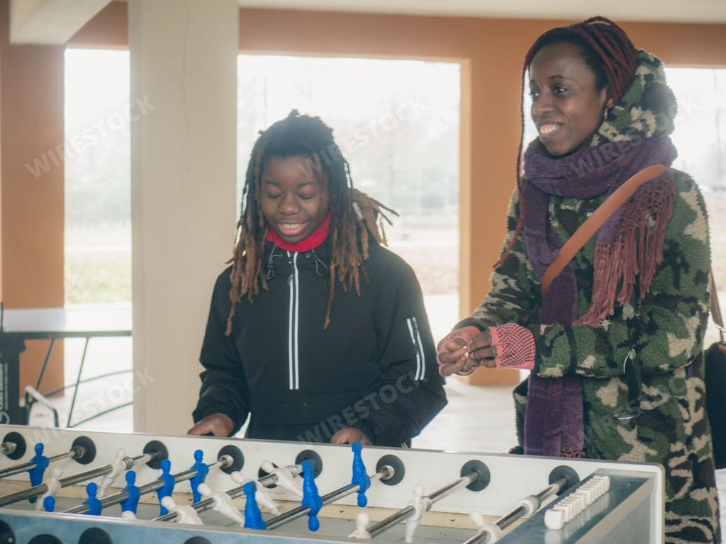 Cheerful young teengaer african american woman dressed in sportswear playing table football aka foosball.