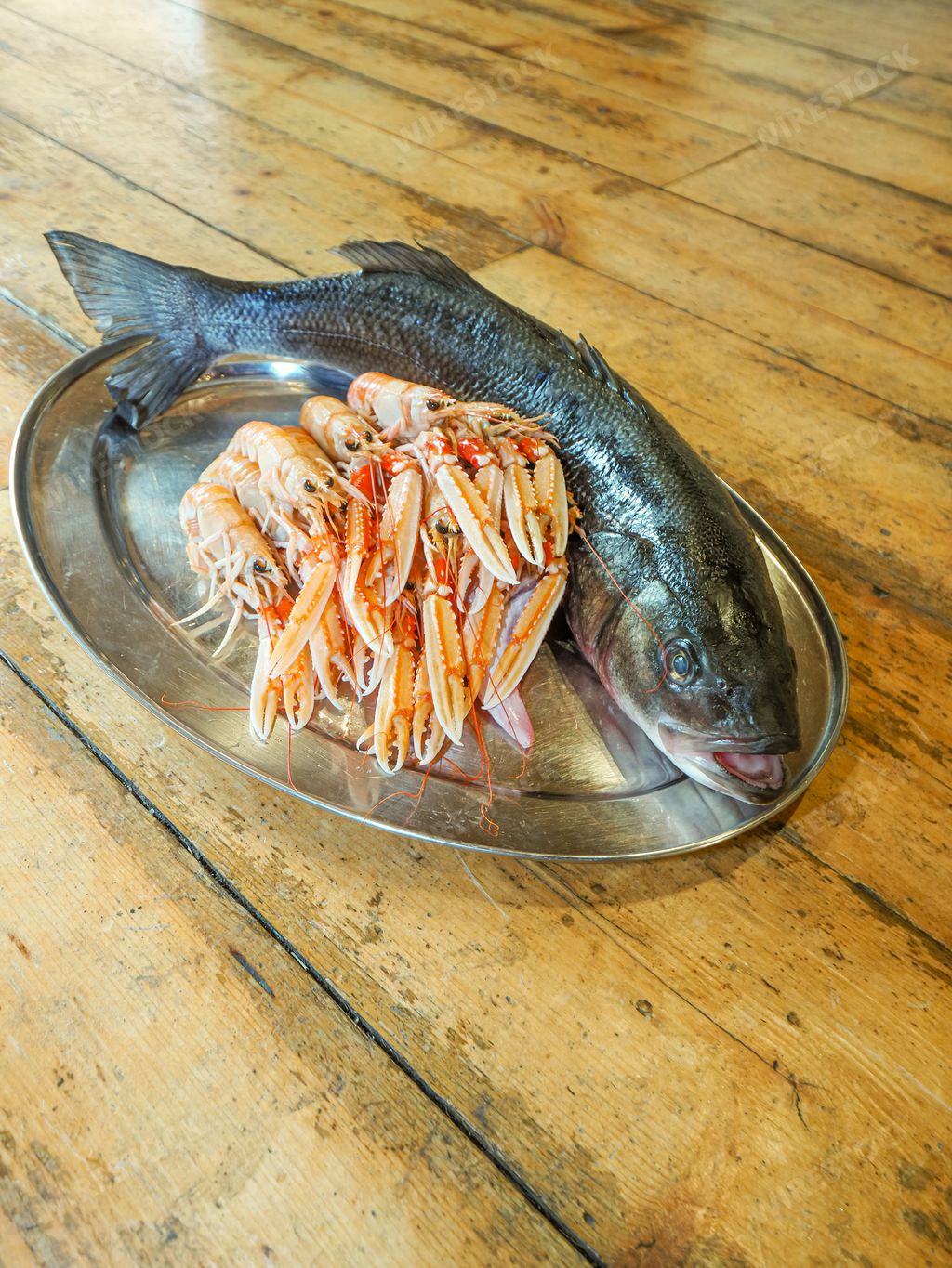 A closeup of fresh Atlantic prawns and a fish on a plate on a table