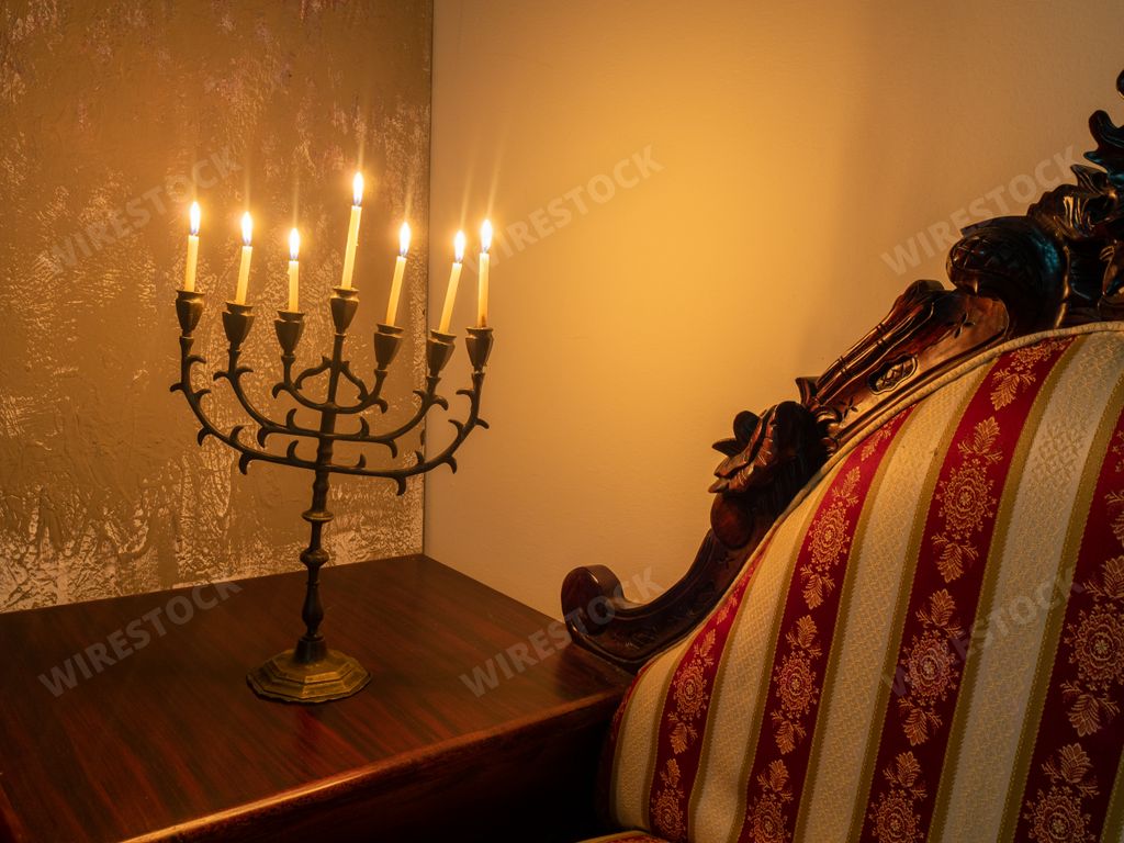 A closeup shot of a seven-branched candelabra with burning candles on the wooden table for Hanukkah