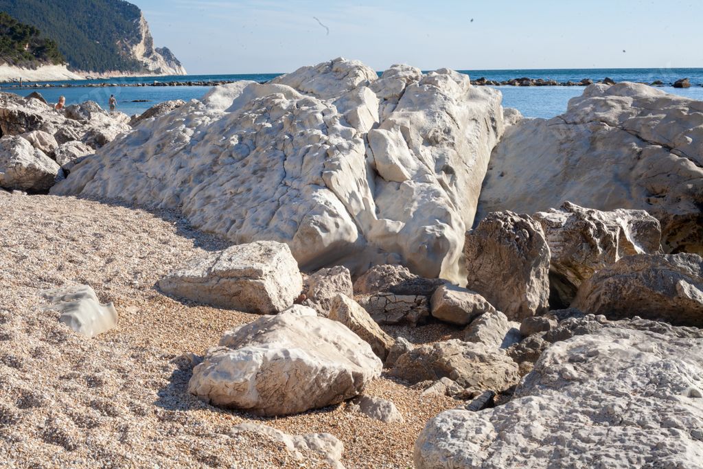A closeup of big rocks on the sand under the sunny sky in Numana, Italy