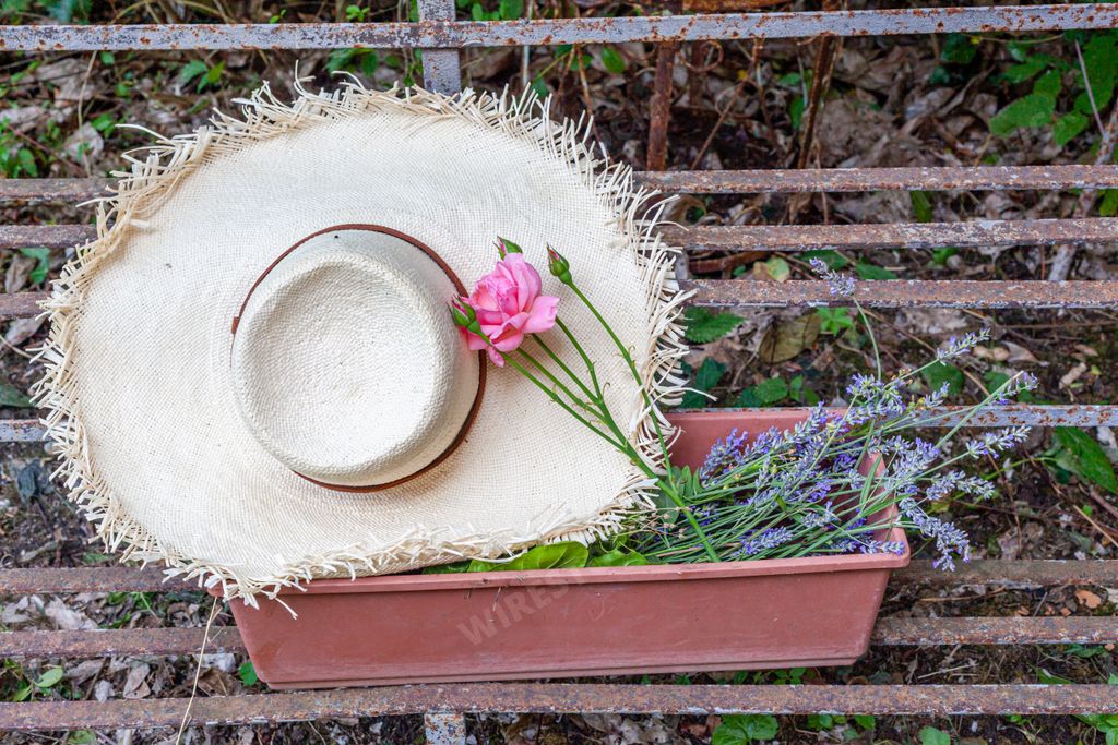 a white straw hat with a rose in a flower pot on a staircase plant stand