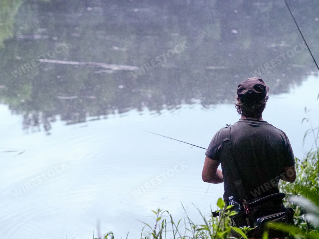 A rear view of man fishing by the river