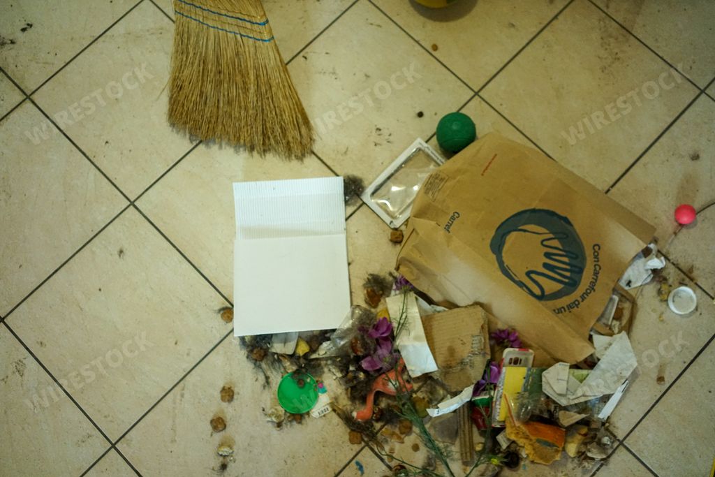 A top view of a broom and trash on a tiled floor during Moving furniture in Milan, Italy