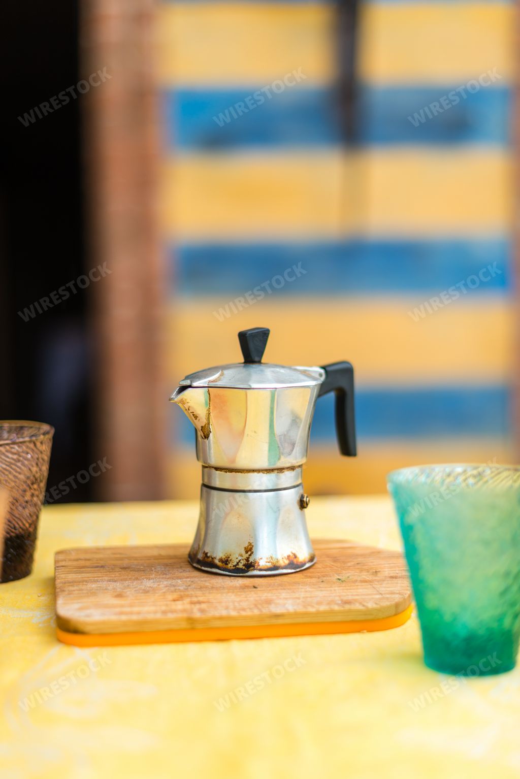 An old geyser coffee maker and glasses on the kitchen table