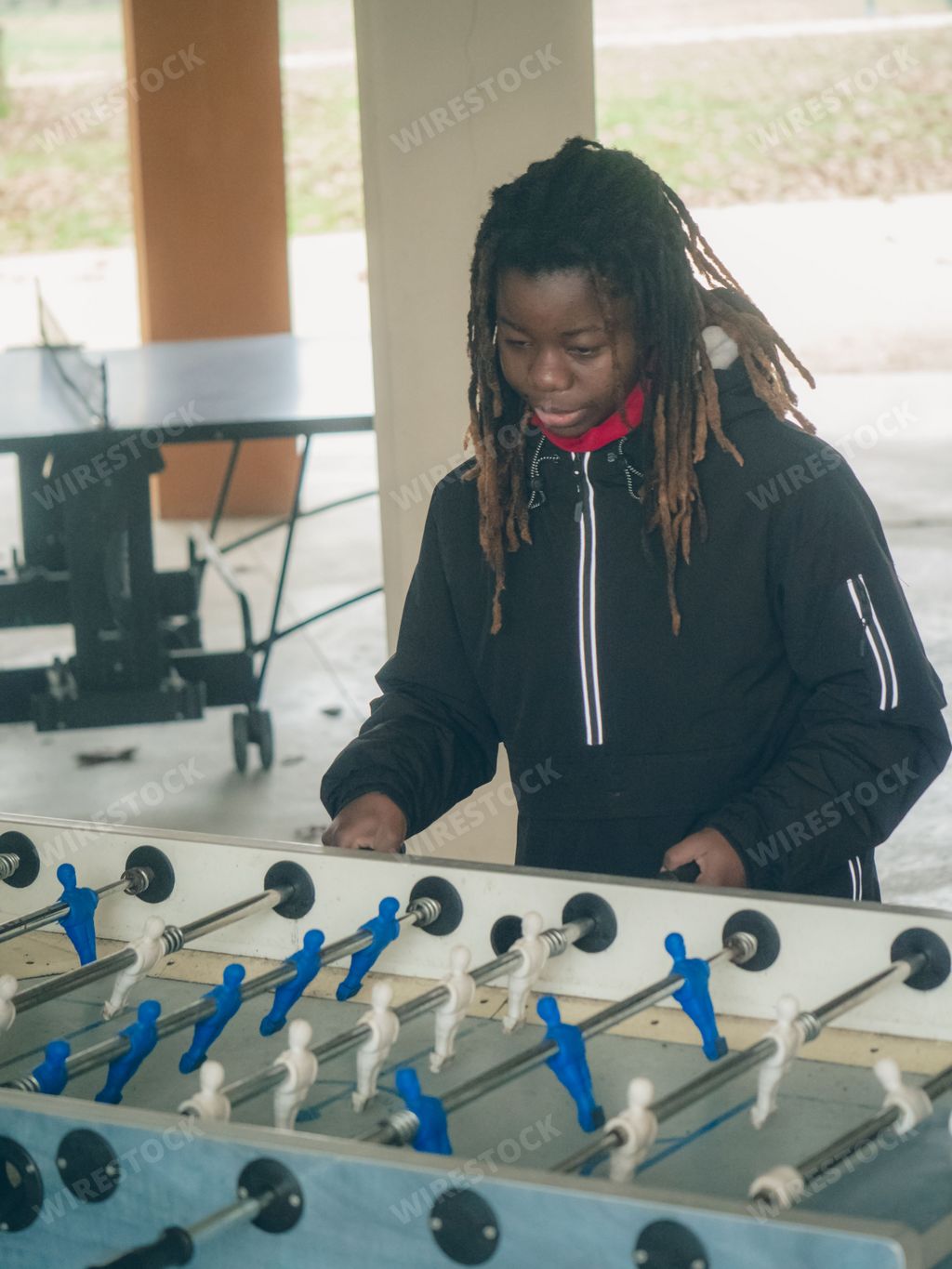 Cheerful young teengaer african american woman dressed in sportswear playing table football aka foosball.