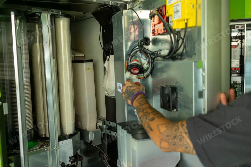 A male filling a coffee vending machine in a self-service grab shop in Milan, Italy