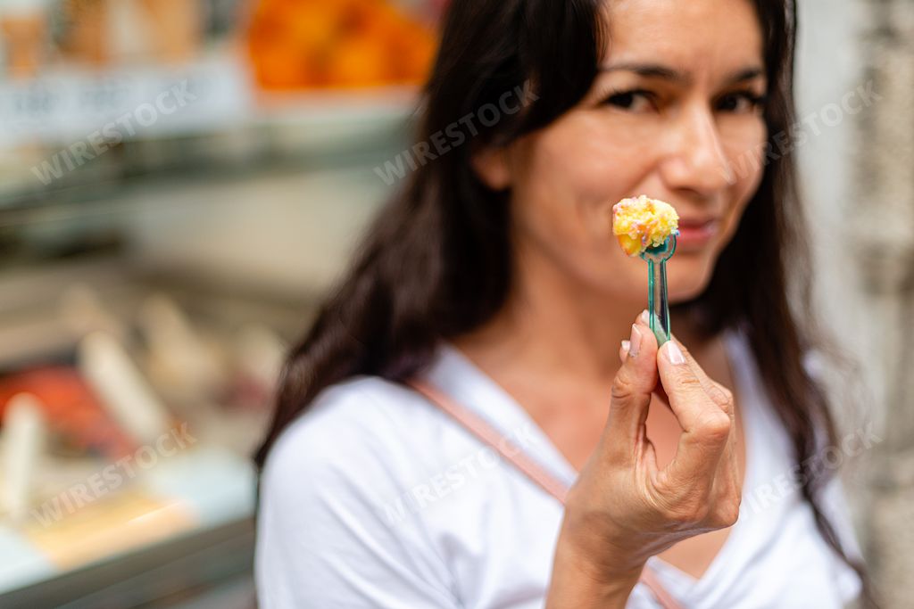 A selective focus of a spoon of ice cream in hands of an Italian female