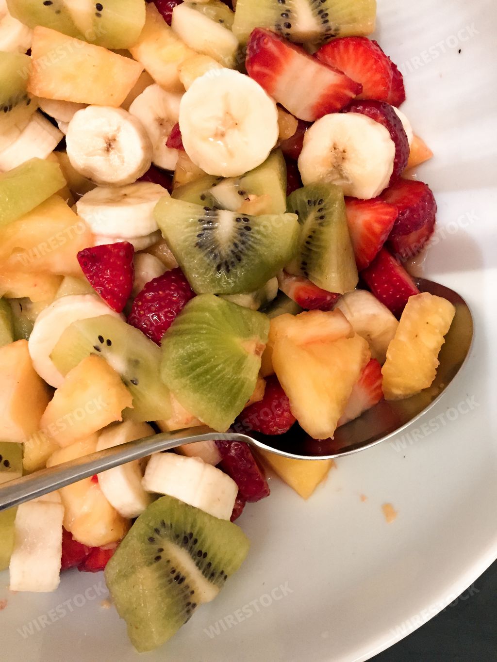 A top view of a fresh fruit salad in a white plate