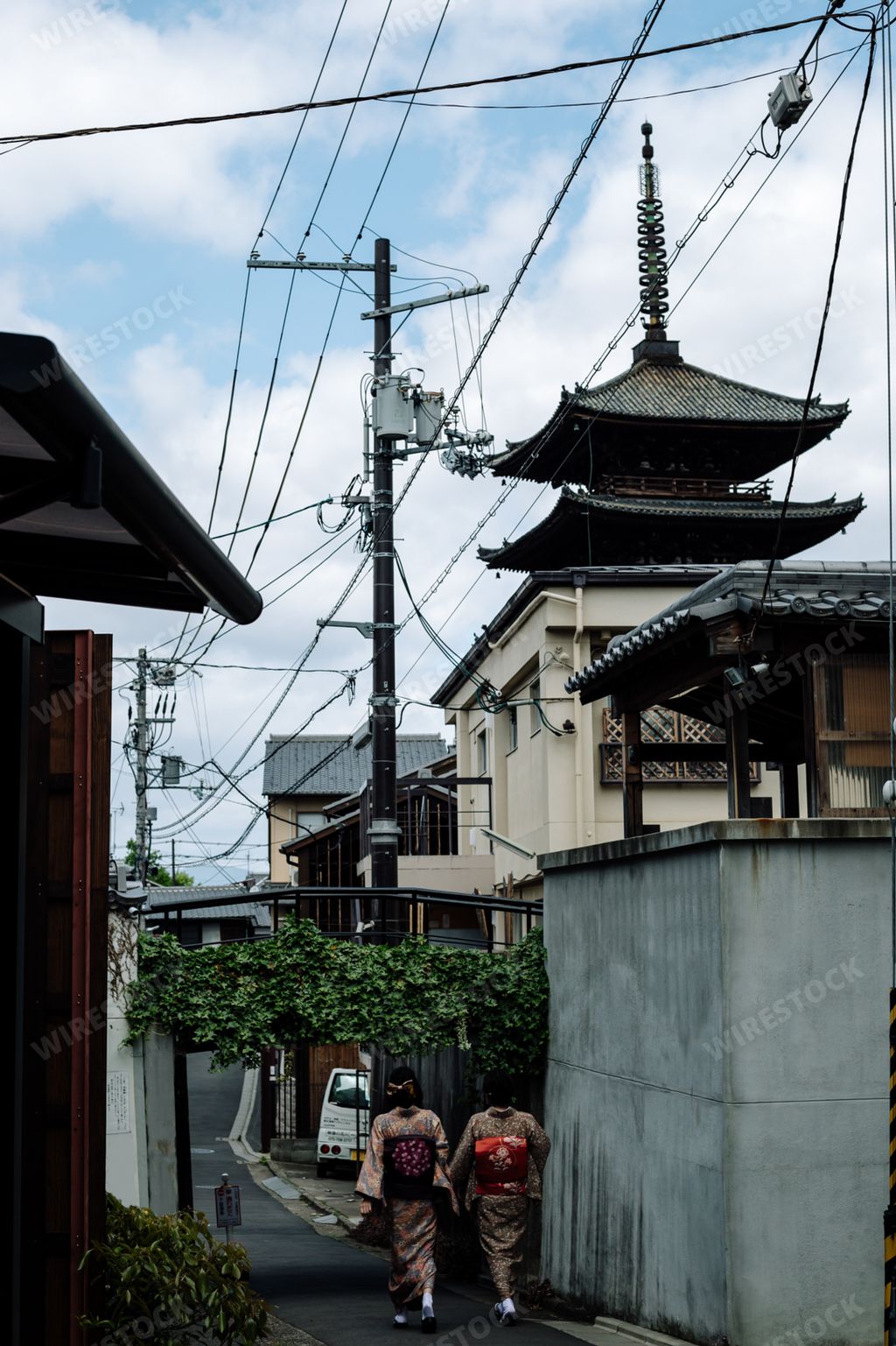 A vertical shot of two young female in kimono walking down the beautiful street
