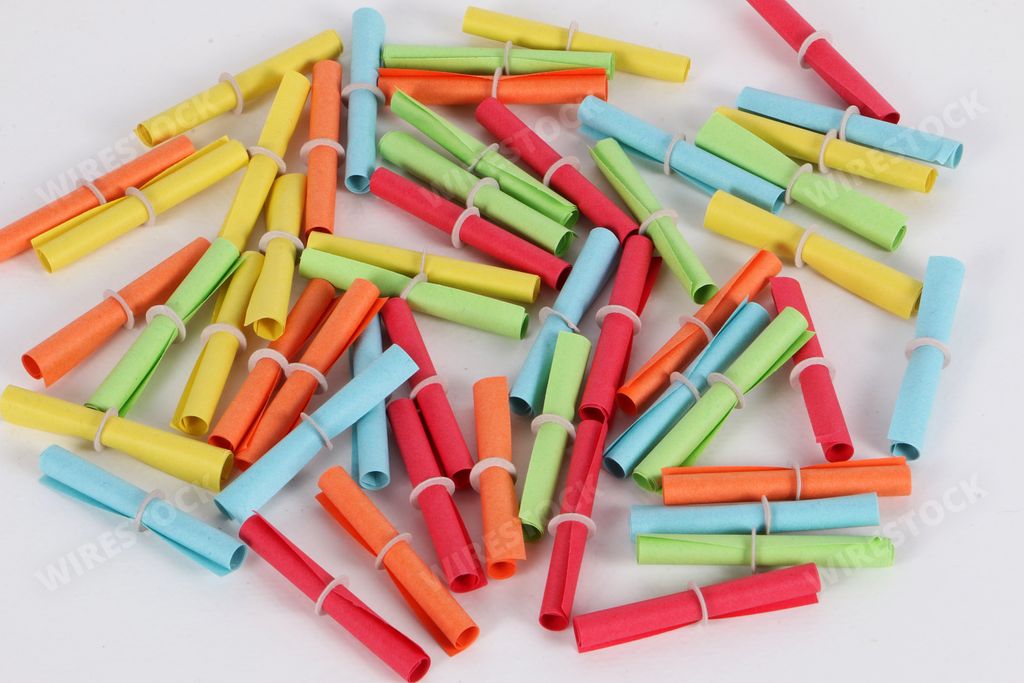 A closeup of a heap of colorful tombola tickets on a white background