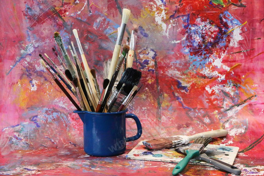 Many different paint brushes in the colorful studio