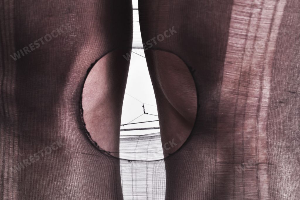 A closeup shot of girls knees in one leg of tights that have a circle ripped in it