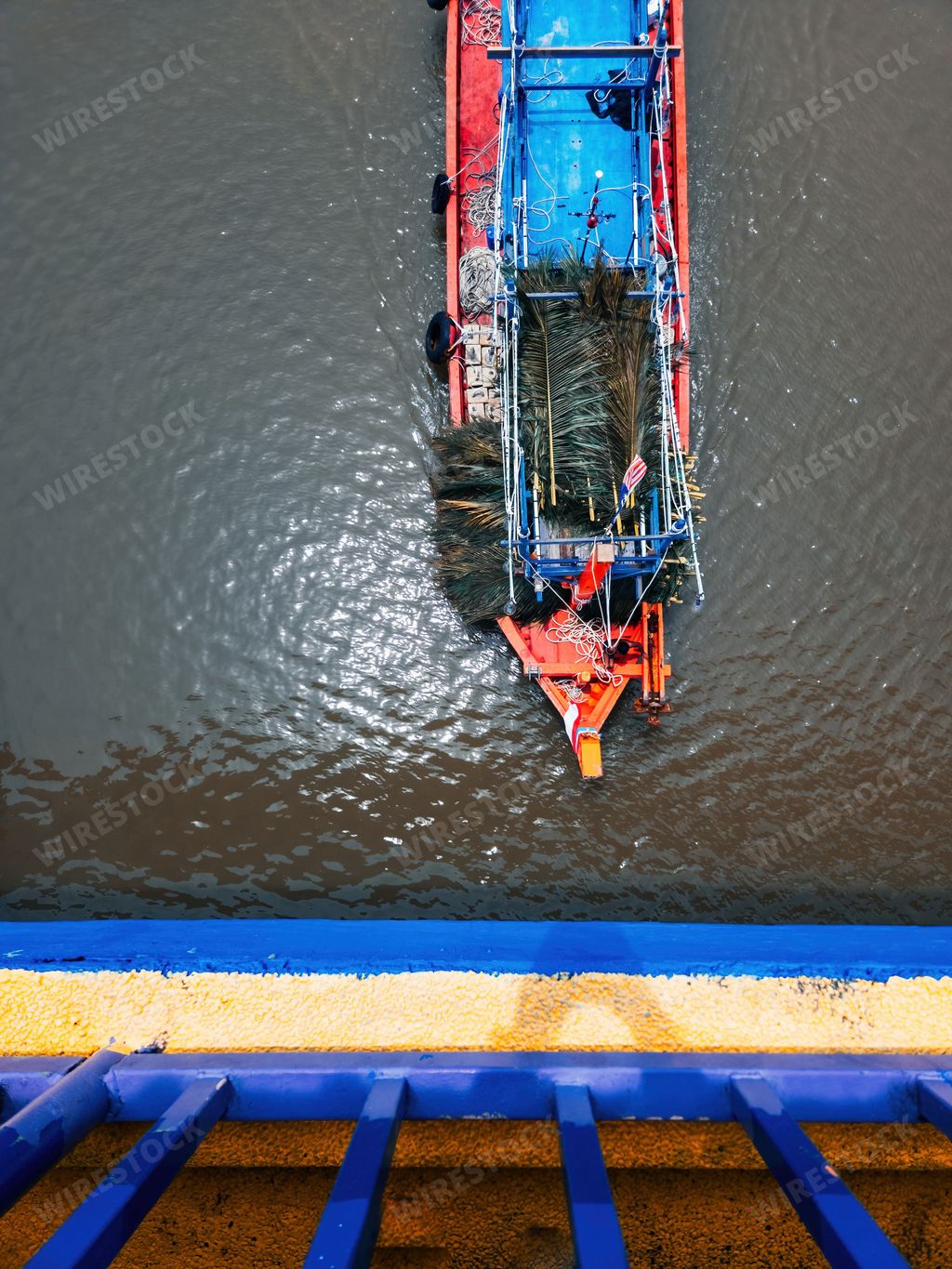 A top view of a boat moving with leaves on the river. View from the bridge.