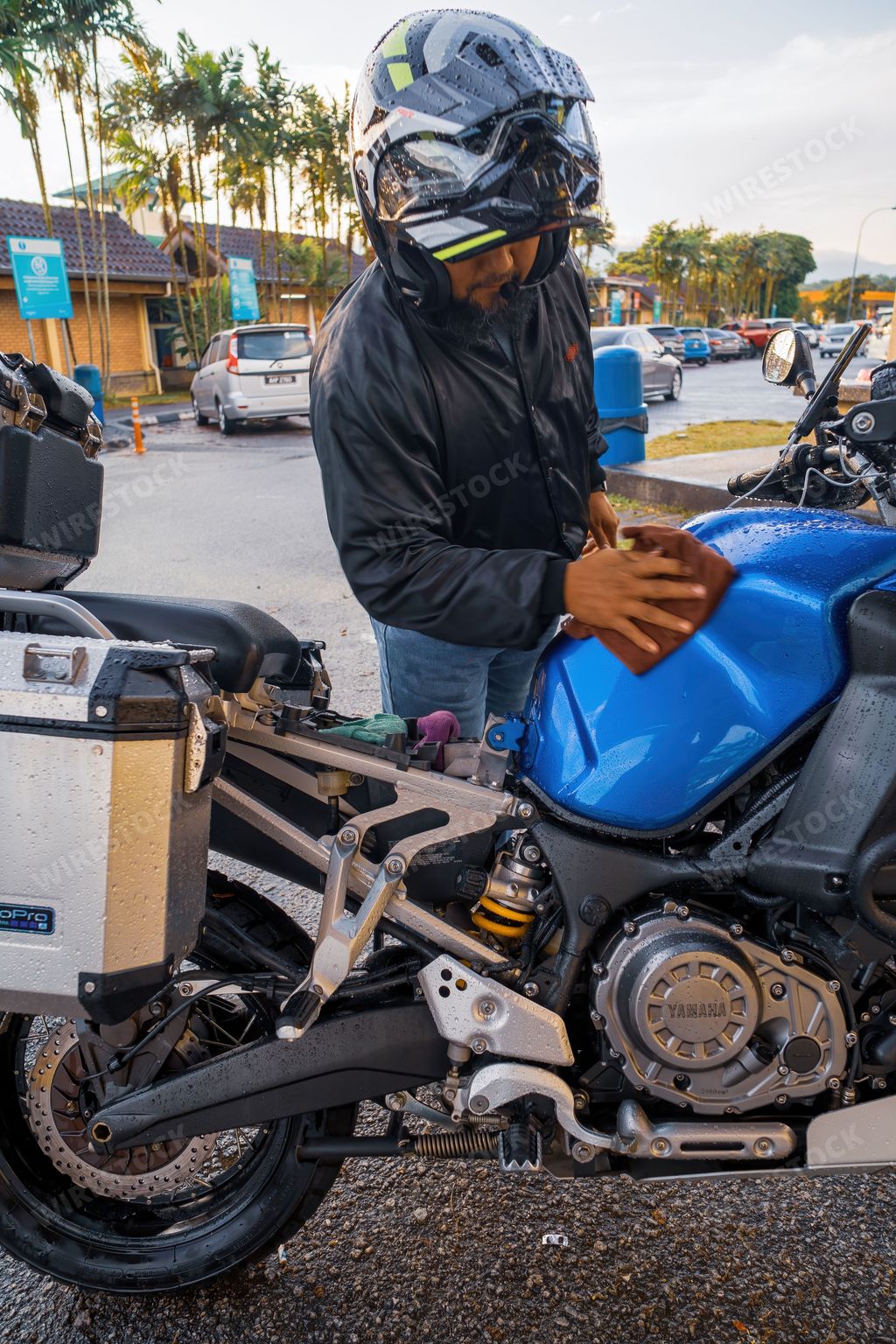 Perak, Malaysia - Aug 12, 2022 Wiping the rain drops on the Yamaha motorcycle at the Rext and Relax stop Tapah.