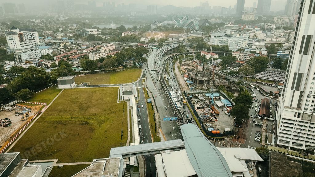 An aerial view of an urban area and highway with buildings in the background in Malaysia.