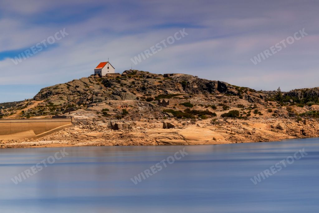 An aerial view of lake surrounded by hills with house in Serra de Estrela