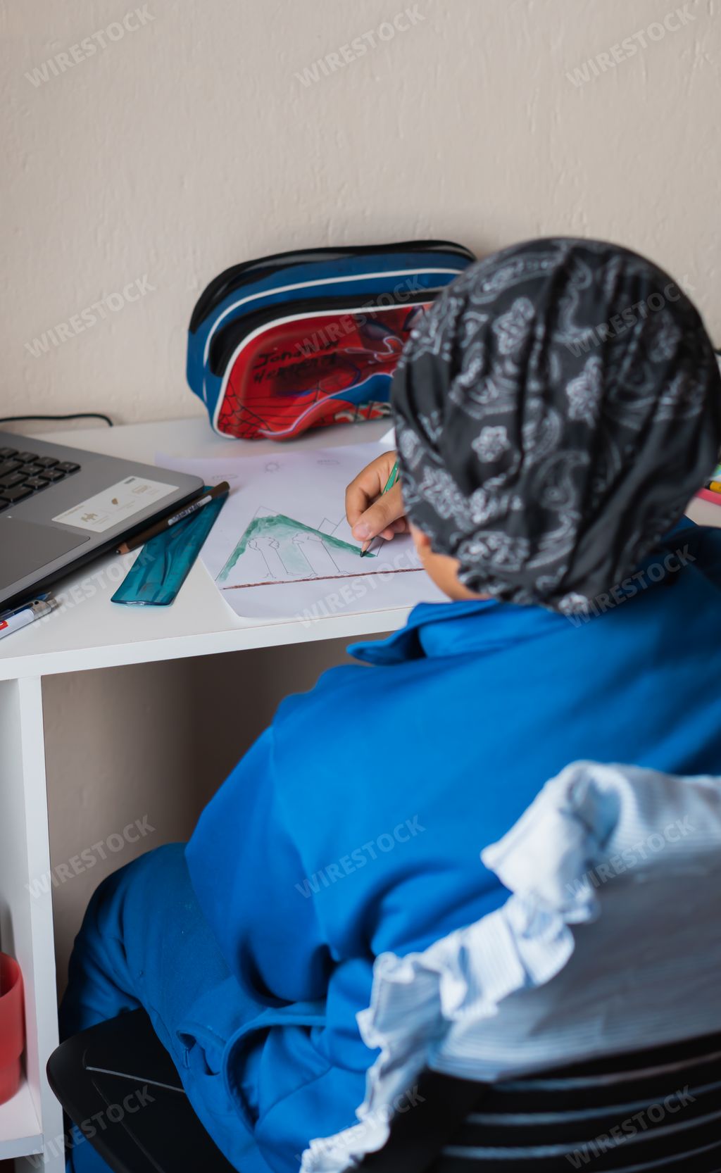 A vertical high angle shot of a child studying at home